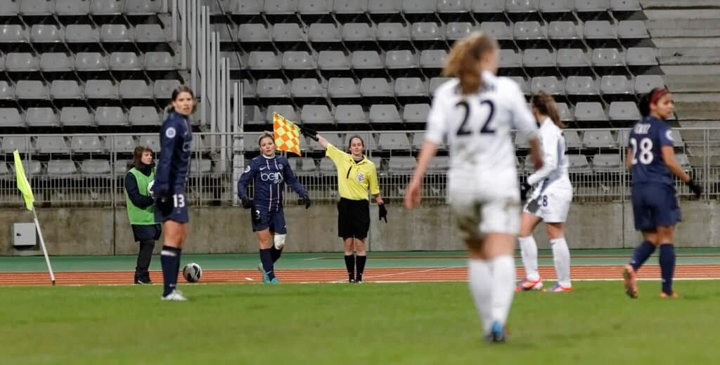Árbitro assistente em ação durante partida de futebol, foto de Pierre-Yves Beaudouin (CC BY-SA 3.0)